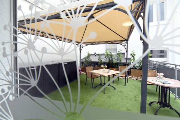 Außenbereich mit Terrasse mit Möbeln und Regenschutz. Attraktive Terrasse mit Überdachung und Sitzmöbeln mit Tisch.