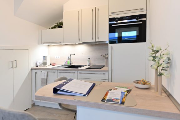 Küche mit moderner Ausstattung. Moderne Küchenzeile mit Spüle, Herd und Kühlschrank, ergänzt durch einen kleinen Tisch.